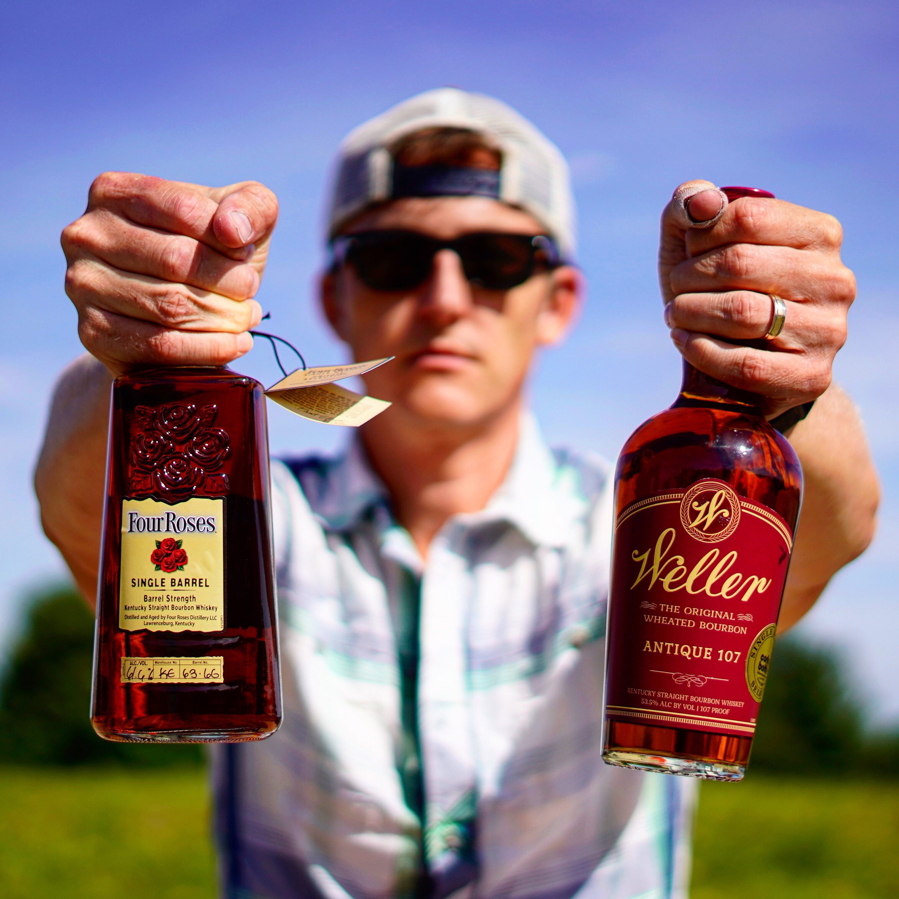 Man holding two bottles with hat and glasses on