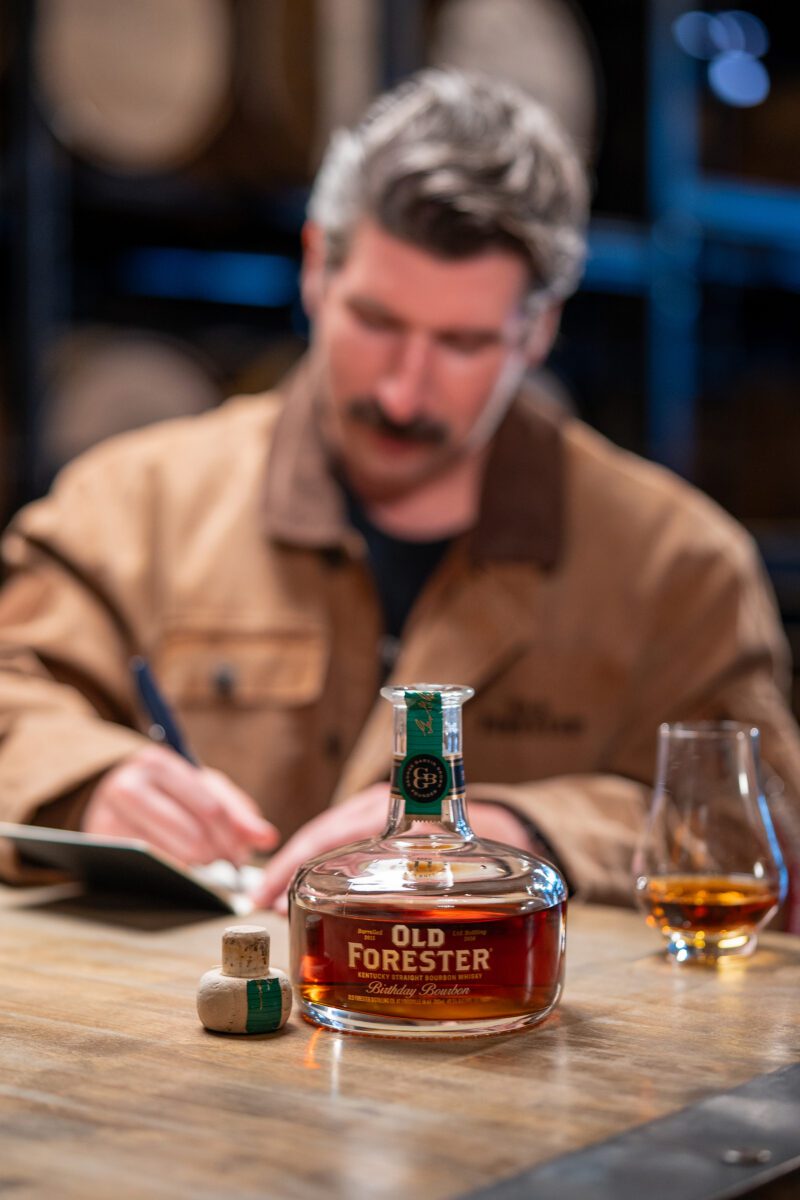Birthday Bourbon on a table with Assistant Master Distiller Caleb in the background